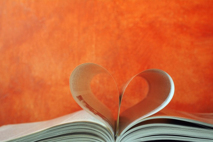 An image of an open book with two pages folded in on themselves to create a heart shape.